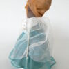 Diva beeld met roestbruin hoofd van ijzer en hoofdoek van textiel op staander, aangekleed met witte vitrage en blauwgroen gewaad.
